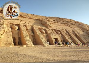 Fațada monumentală surprinsă în timpul unei Excursie in Abu Simbel, prezentând statuile gigantice ale lui Ramses al II-lea și turiștii care explorează situl arheologic.